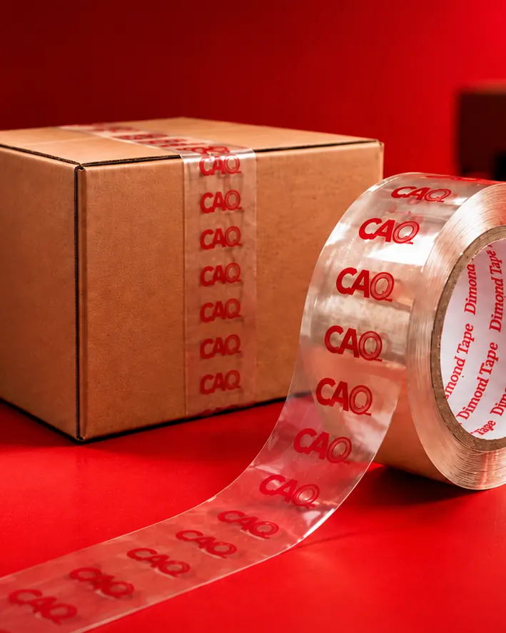 Caja cerrada con cinta transparente impresa con el logotipo CAO y rollo de la misma cinta sobre fondo rojo